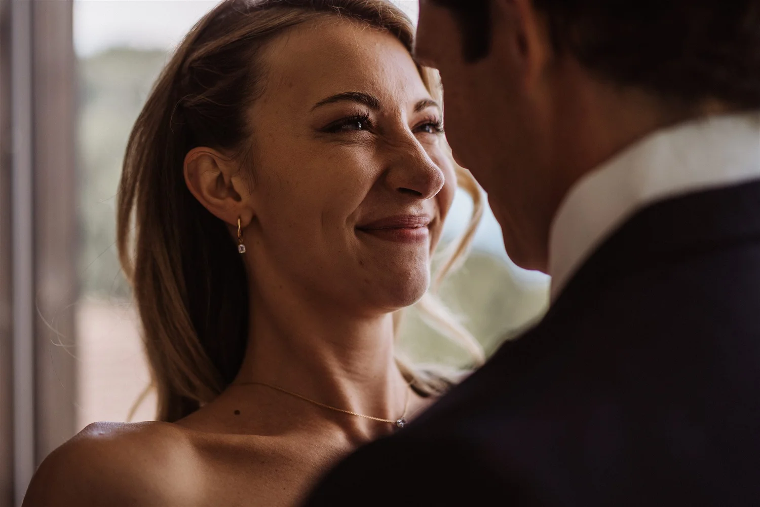 A woman with light skin and brown hair smiling at a man with dark skin, close-up view of their faces with the woman looking joyful.