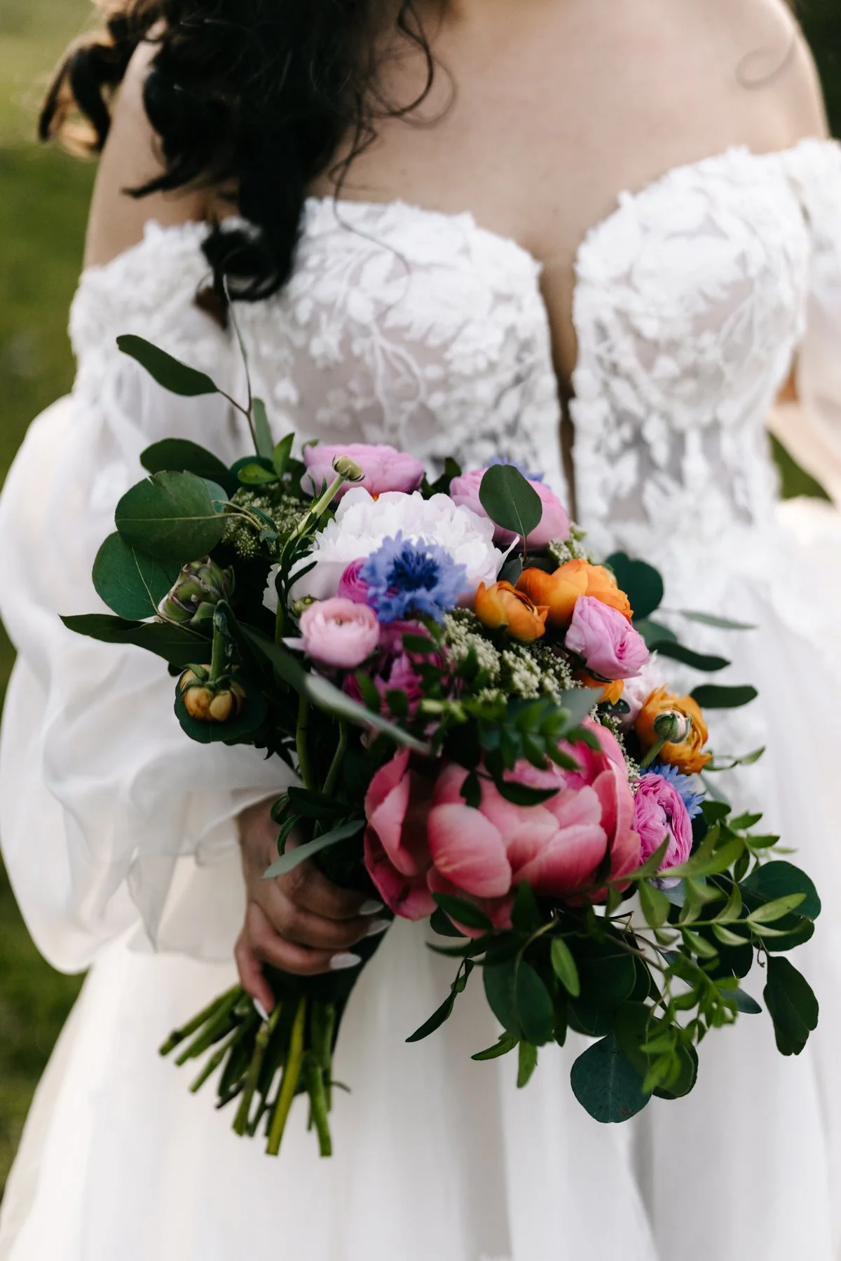 A woman in a white dress holding a colorful bouquet of flowers.