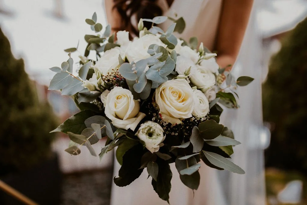 Close-up of a wedding bouquet with white roses and greenery.