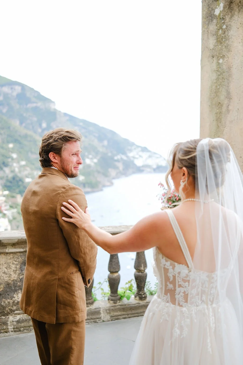 A bride and groom sharing a moment on a terrace overlooking a river and hills during their wedding.