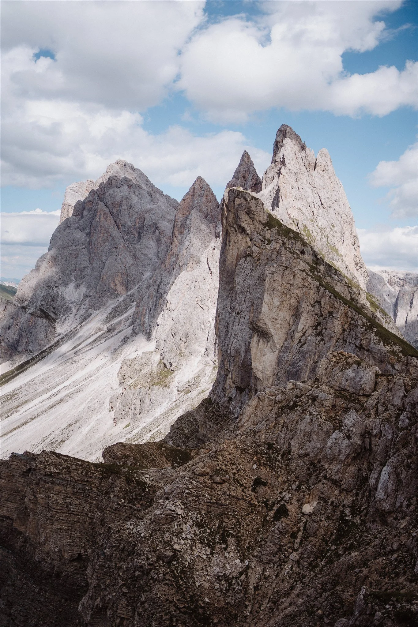 View of rugged mountain peaks with partly cloudy sky in the background.