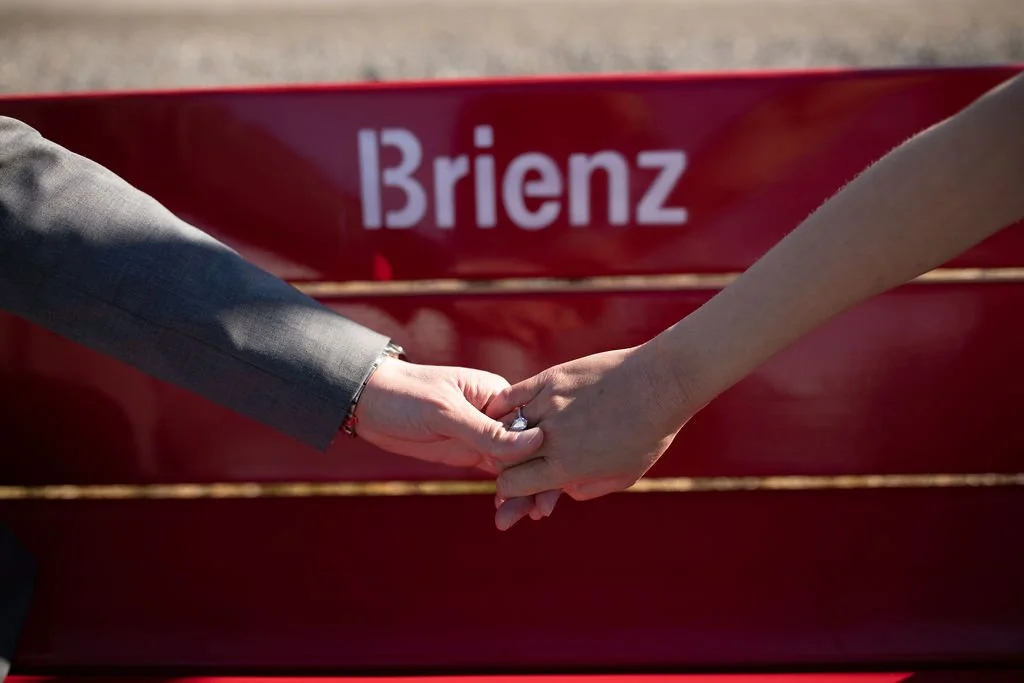 Two people holding hands in front of a red boat with the name 'Brienz' on it.