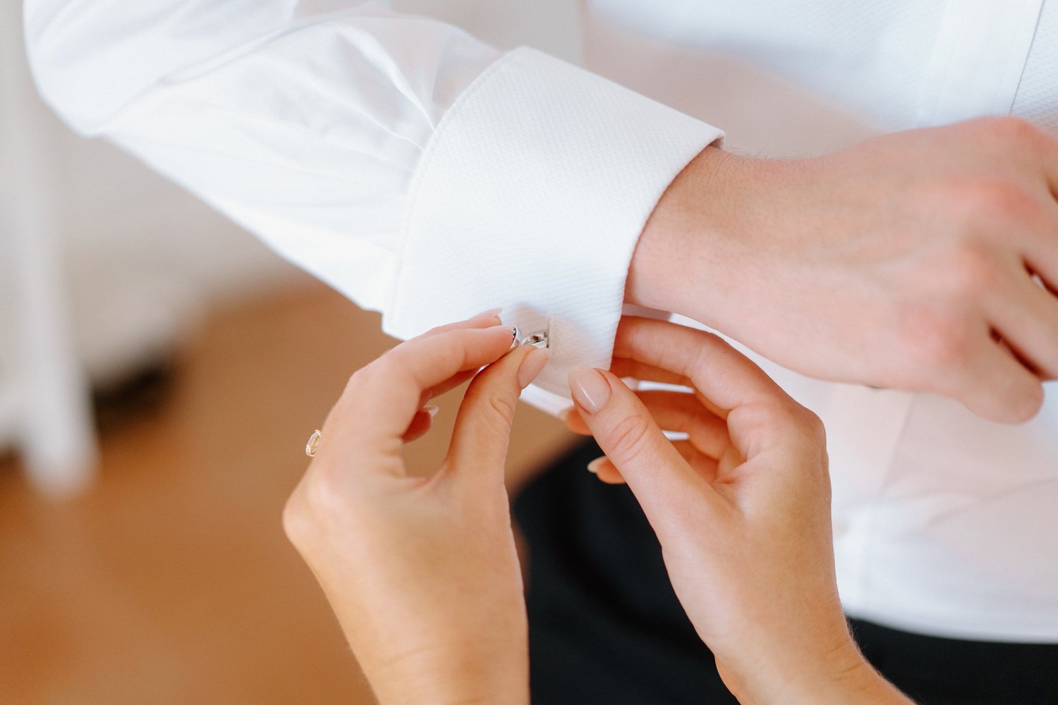 Person in a white shirt buttoning their cuff