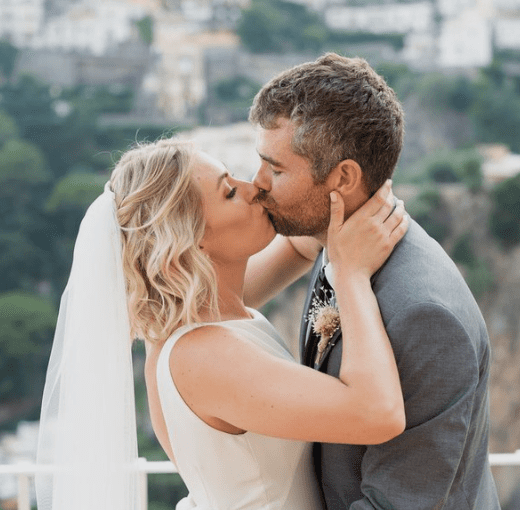 Bride and groom kissing outdoors during a wedding ceremony.