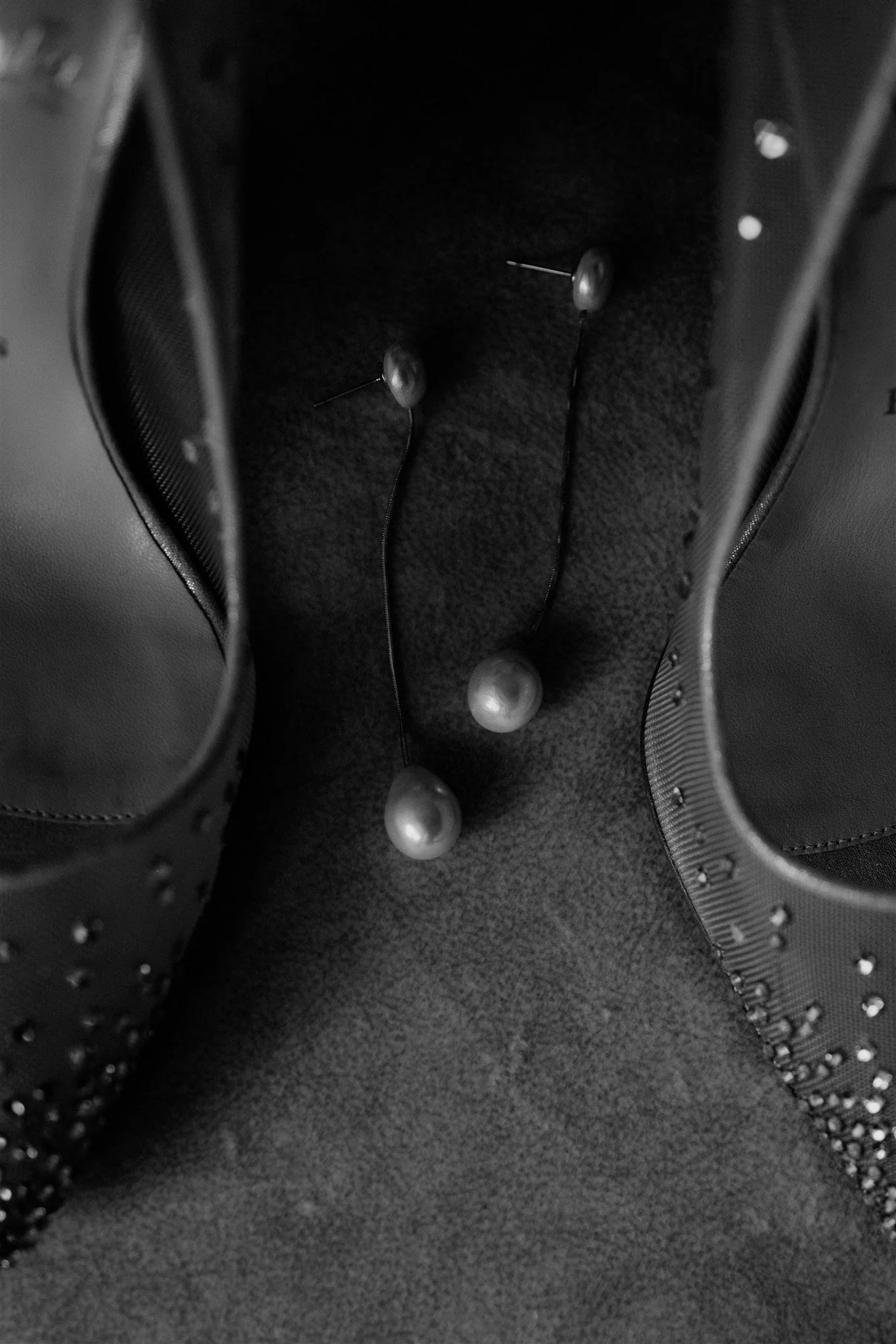 A view inside a black leather sneaker with a textured sole. There are four metal stud-like decorations and three spherical metallic objects arranged inside.