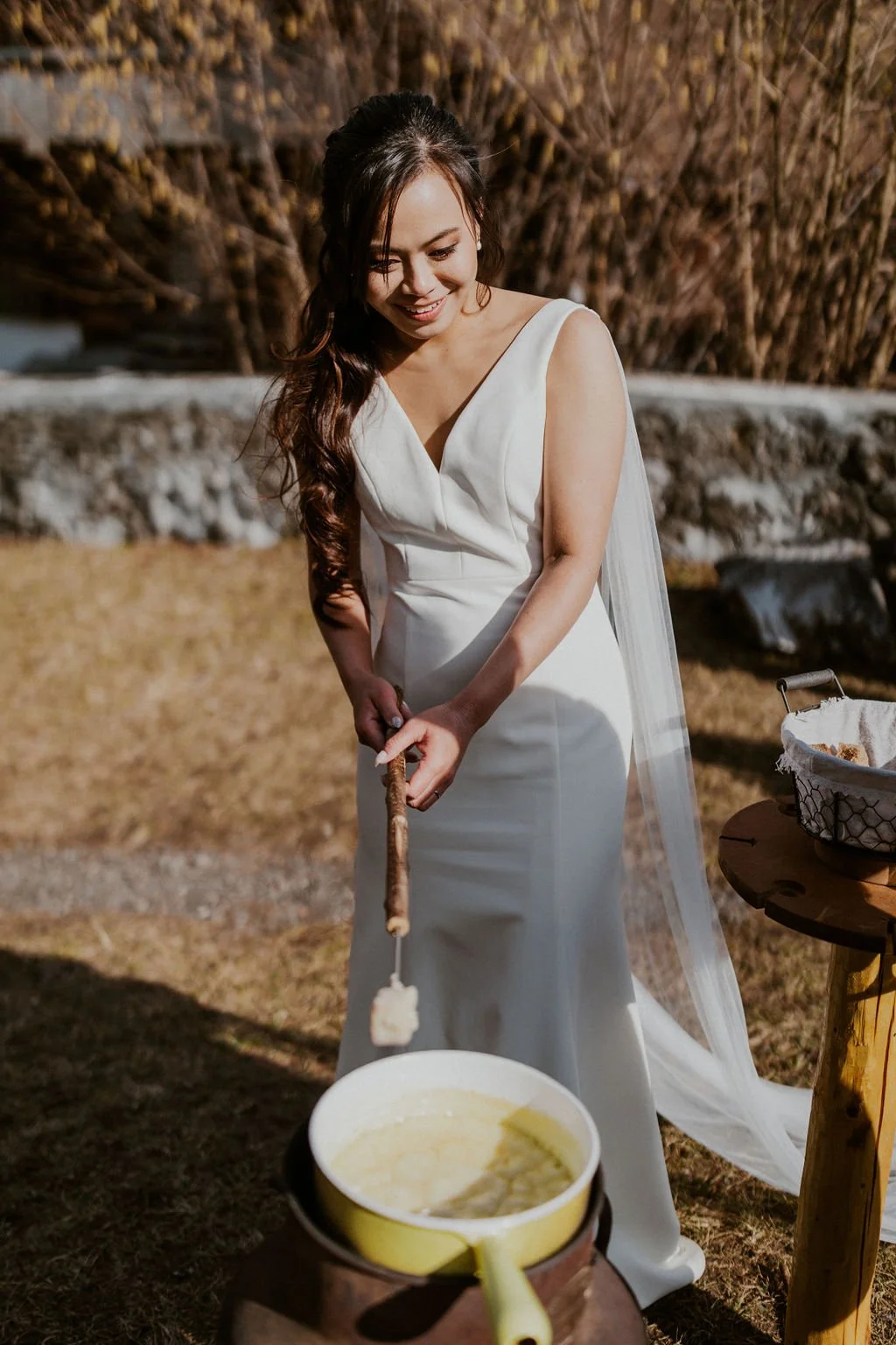 Woman in a white dress making s'mores over a fire outdoors.