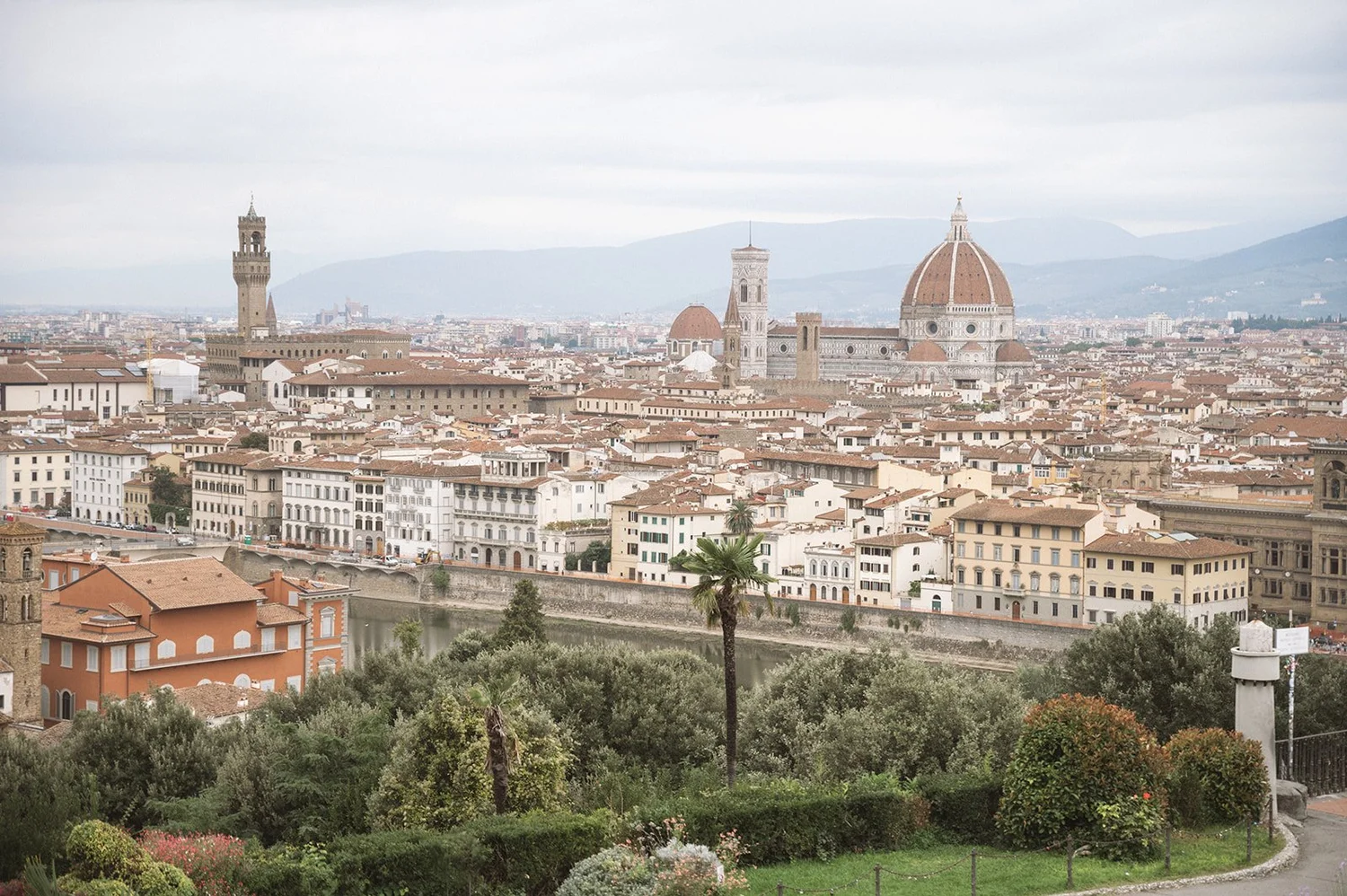 View of Florence, Italy, with the Florence Cathedral's dome, bell tower, and cityscape in the background, as seen from a green park in the foreground.