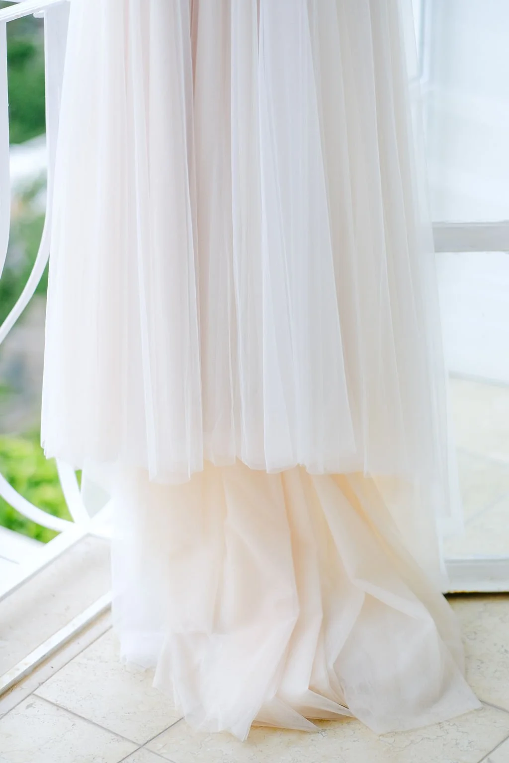 White sheer curtain hanging in front of a door or window with green outdoor view visible.