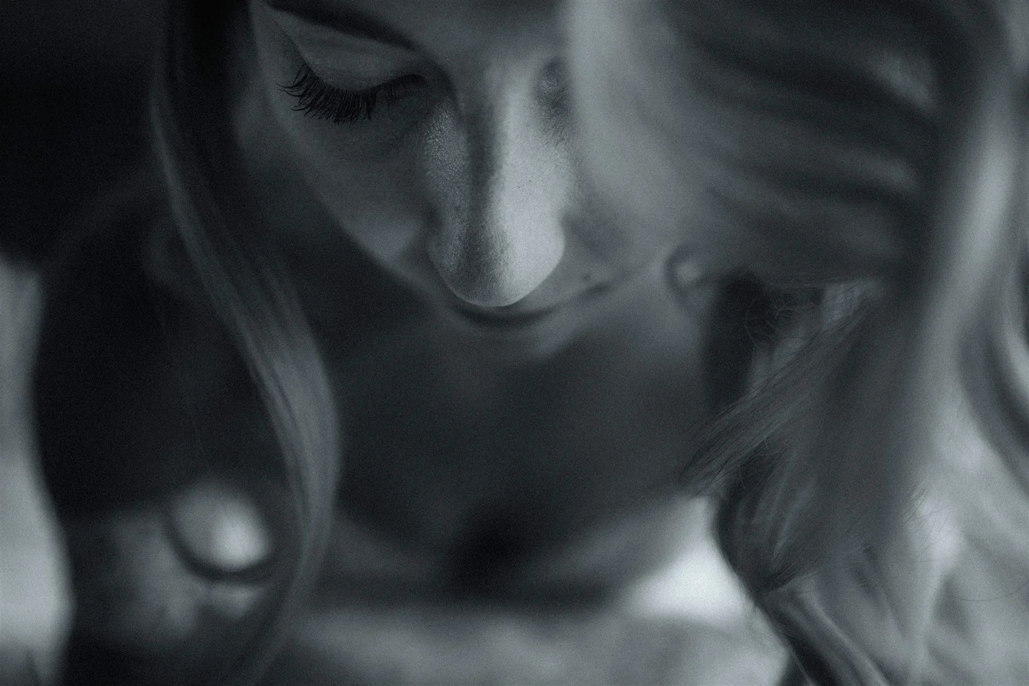 Close-up of a person's face with eyes closed, in black and white.