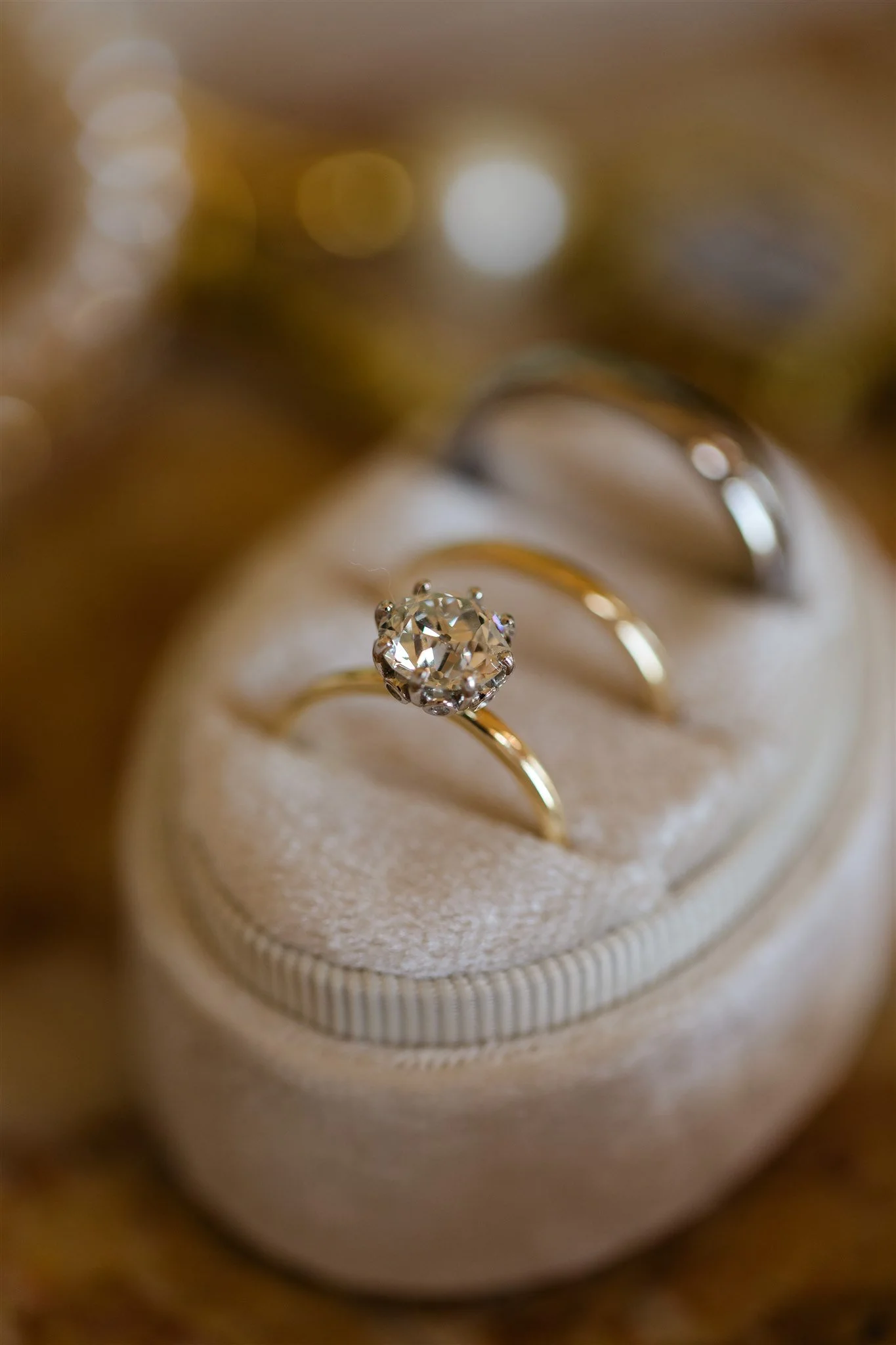 Close-up of a diamond engagement ring with a large center stone, set in a gold band, resting in a jewelry box.
