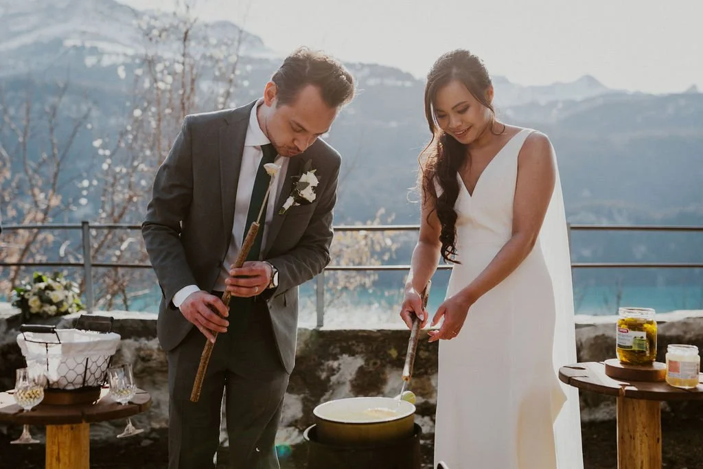 A bride and groom performing a traditional candle lighting ceremony outdoors during their wedding, with a mountain backdrop.