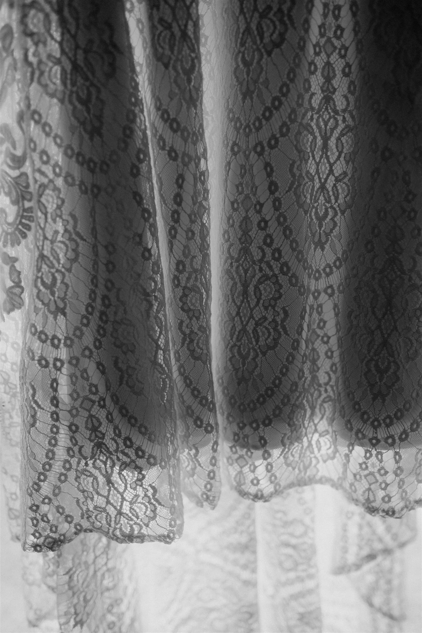 Close-up of black lace fabric with intricate floral and geometric patterns in black and white.