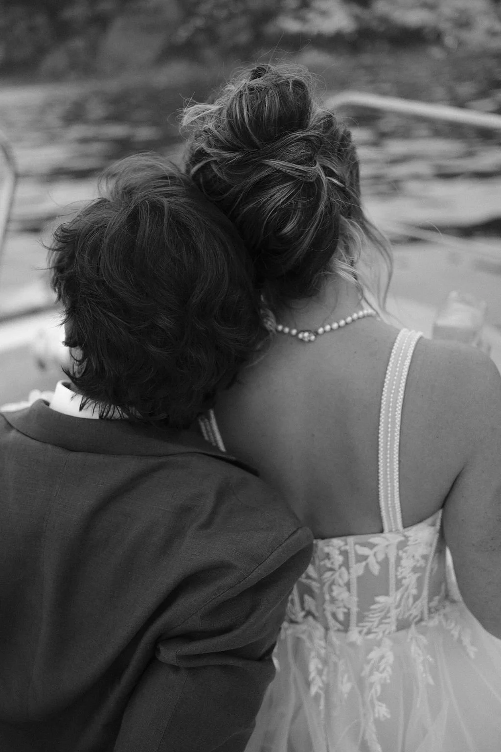 A black and white photo of a couple embracing, with their heads touching, at what appears to be a formal outdoor event.
