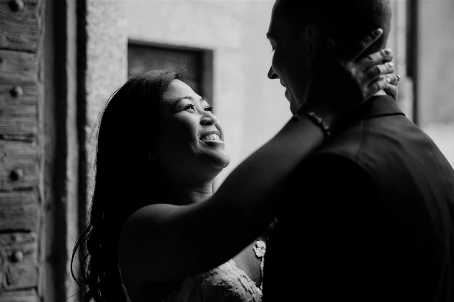 A black-and-white photo of a couple embracing, smiling and looking into each other's eyes, in an intimate moment.