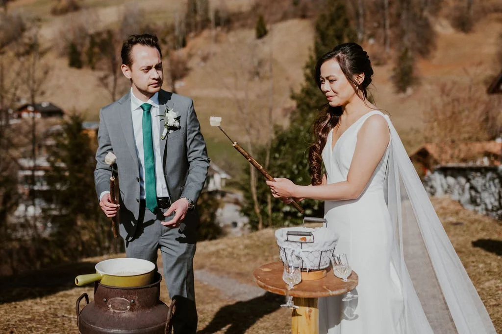A bride and groom exchanging rings outdoors during their wedding ceremony in a mountainous area.