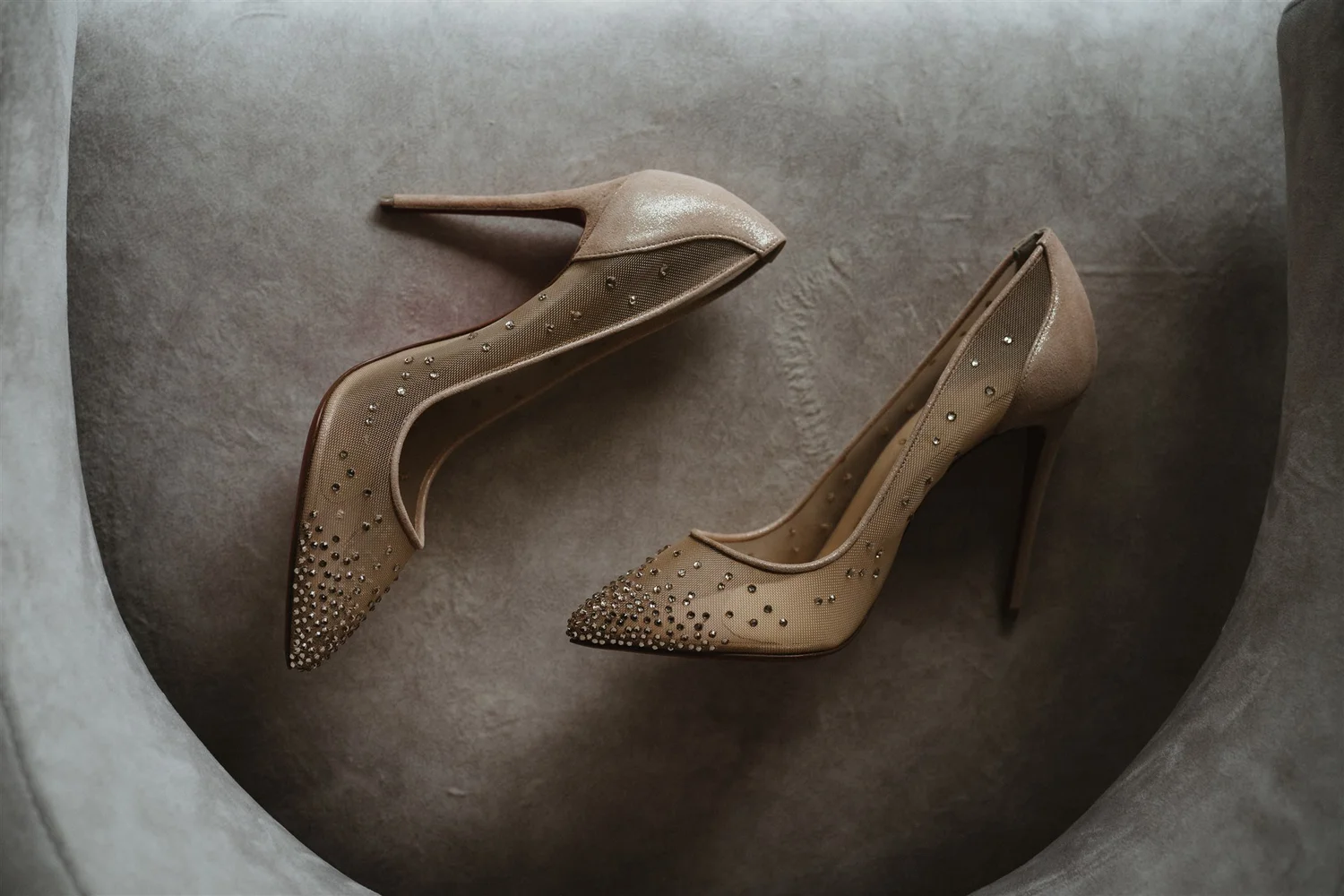 Pair of beige high-heeled shoes with rhinestone embellishments.