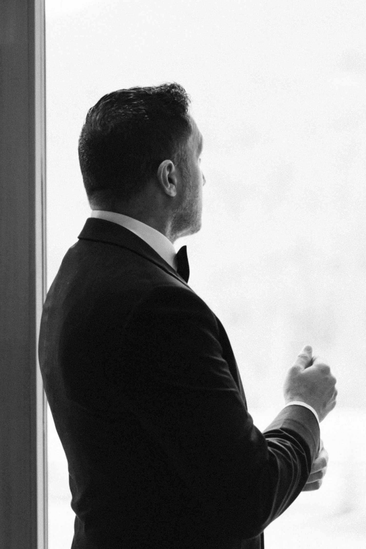 Man in tuxedo looking out a window