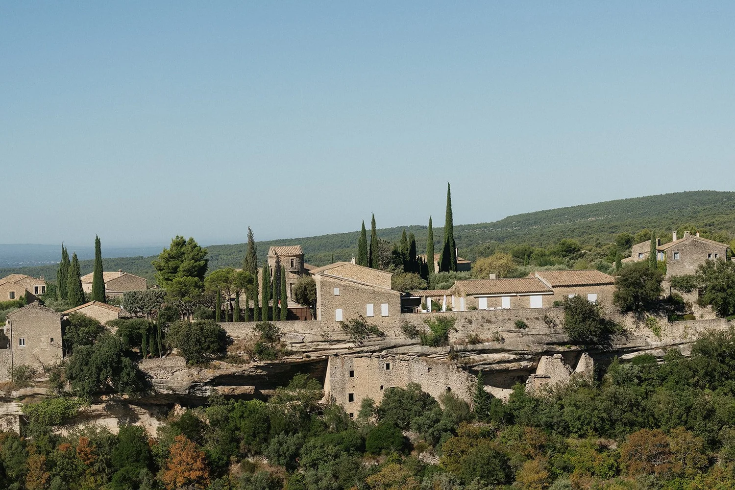 Village with stone houses and tall cypress trees on a hillside