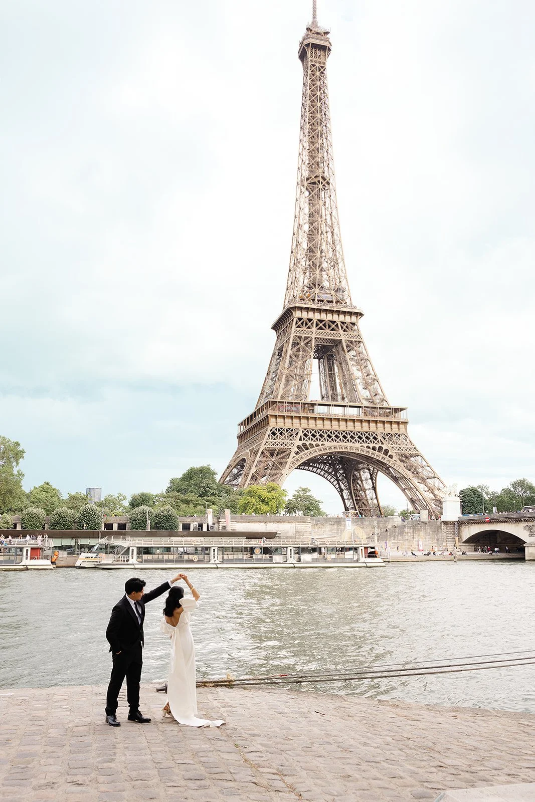 A couple dancing near the Seine River with the Eiffel Tower in the background in Paris, France.