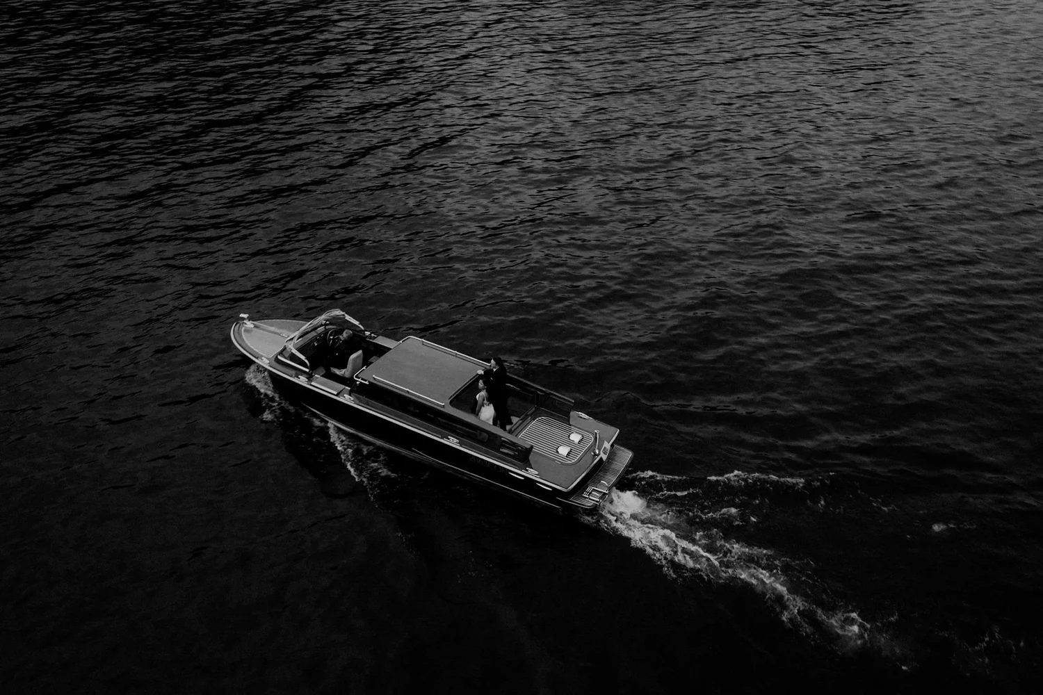 A motorboat with three people on board moving across a dark body of water.