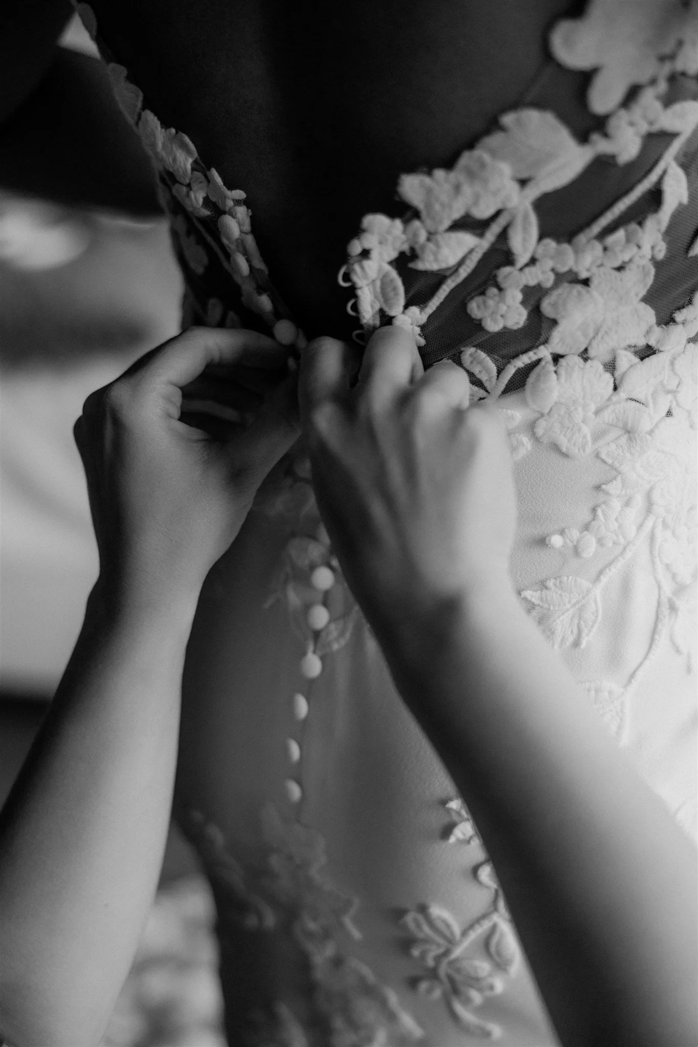 Close-up of hands adjusting a piece of clothing with embroidered floral details, likely a dress or a fabric with decorative embroidery.