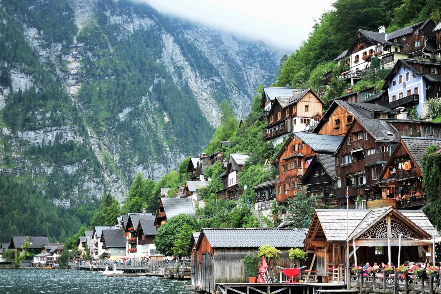 Colorful buildings lining a lake with mountains in the background and partly cloudy skies.