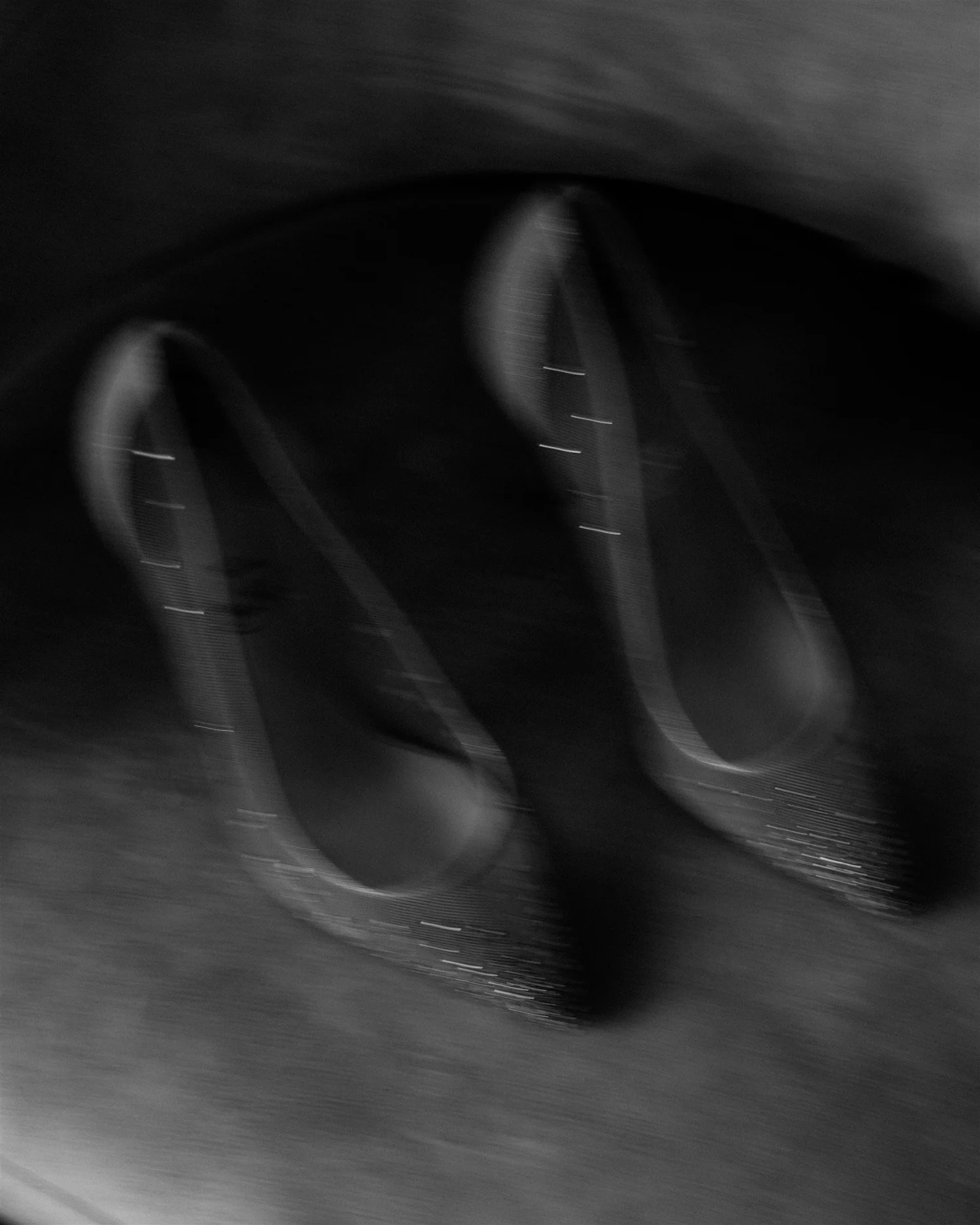 Motion-blurred close-up of two black bicycle tires and wheels on a paved surface.