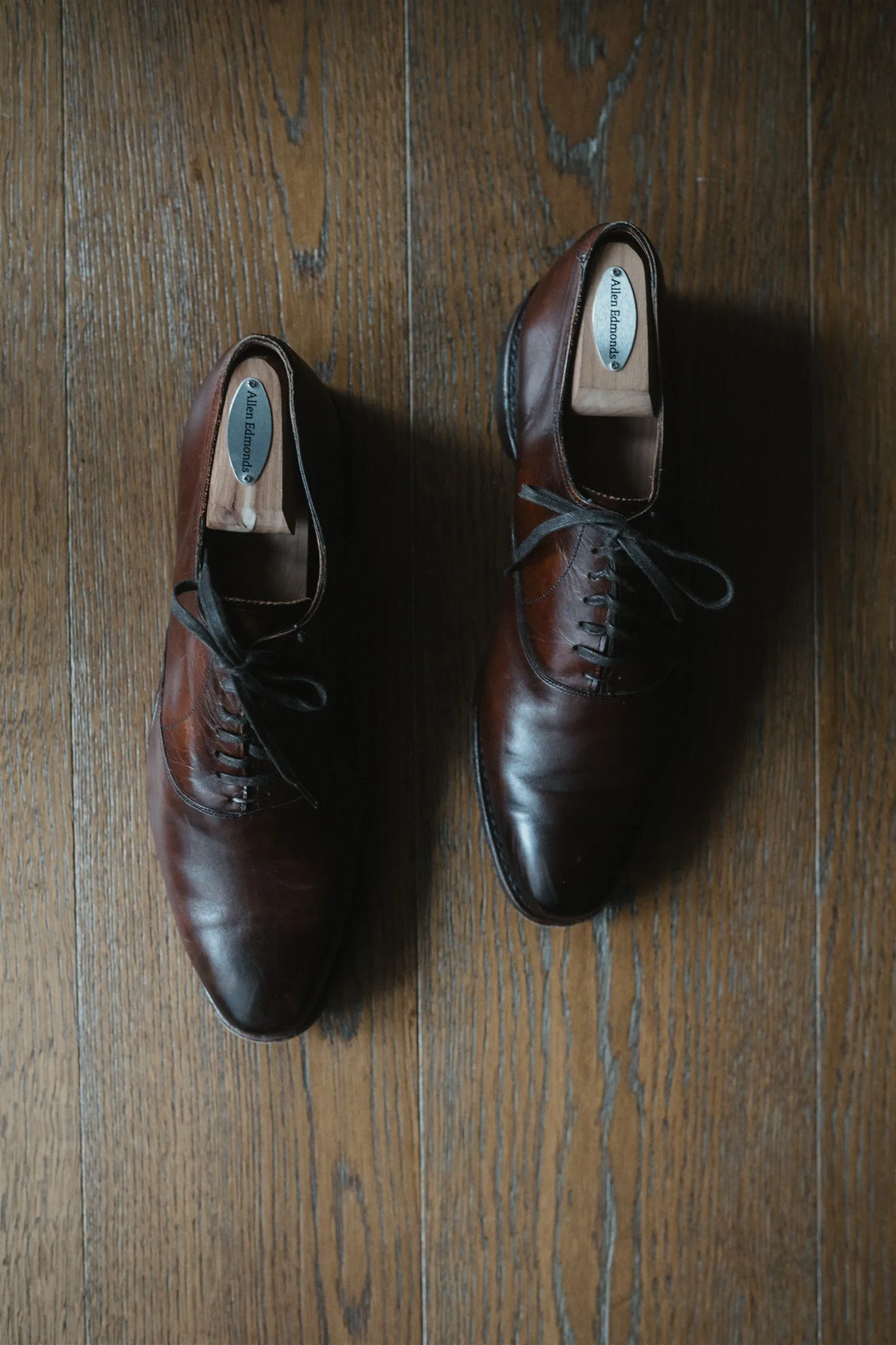 Pair of brown leather dress shoes on a wooden floor.