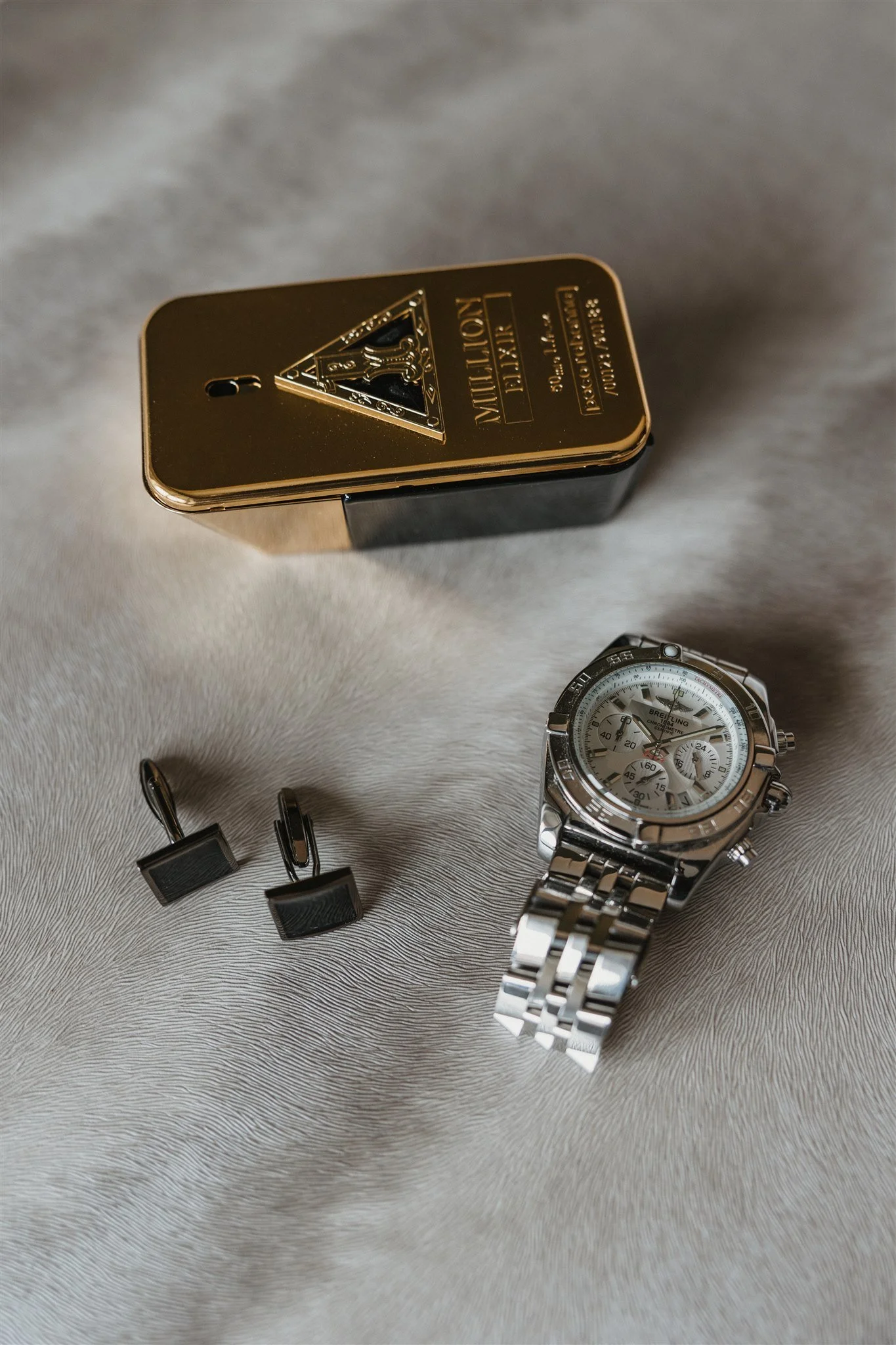 A luxury wristwatch with a white dial and three subdials, a metal bracelet, and chronograph features.