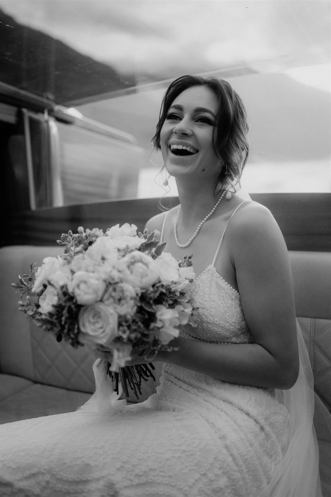 A woman in a wedding dress is smiling and holding a bouquet of flowers.