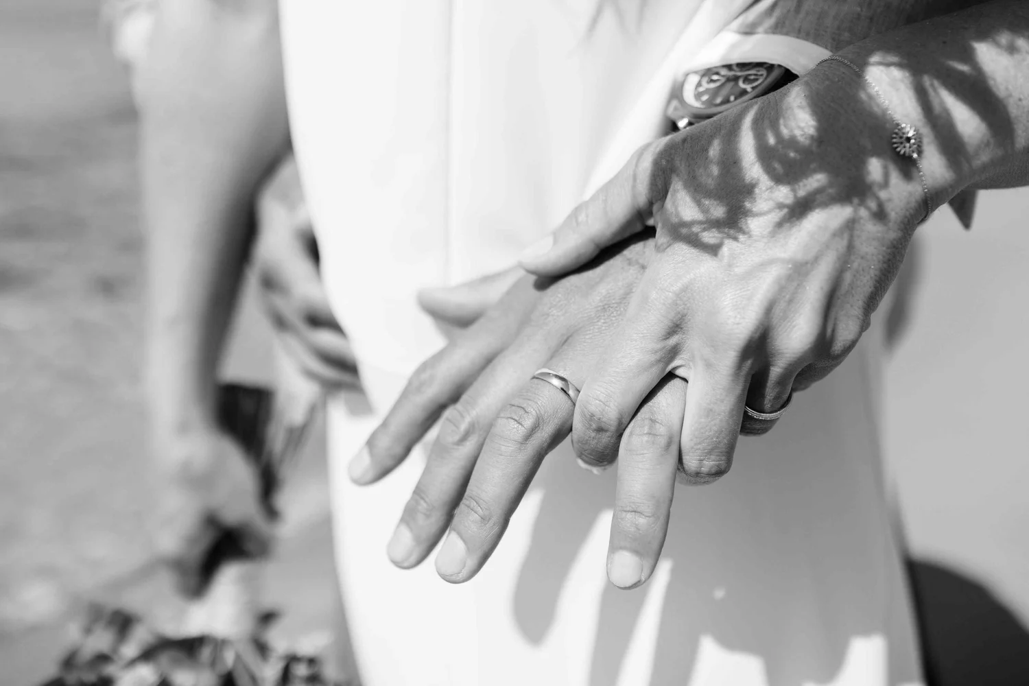 Close-up of two hands gently touching, with one hand having a watch and a ring, and the other with a jewelry ring, symbolizing connection or affection.