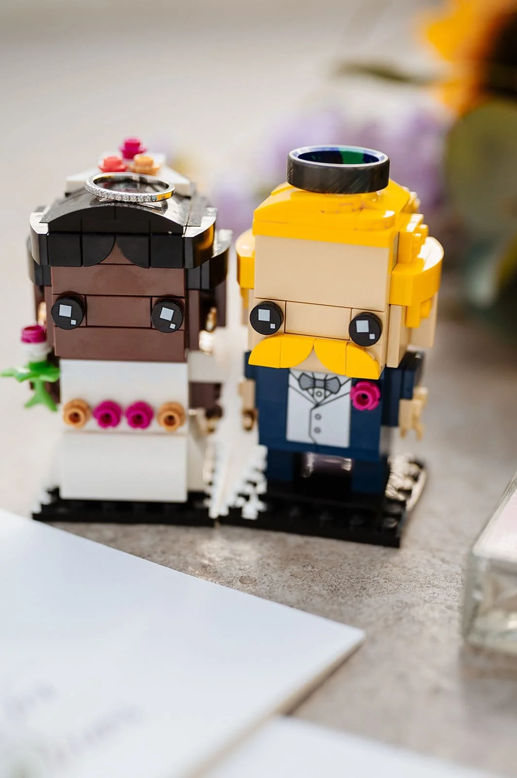 Lego figures of a bride and groom with wedding accessories on a table.