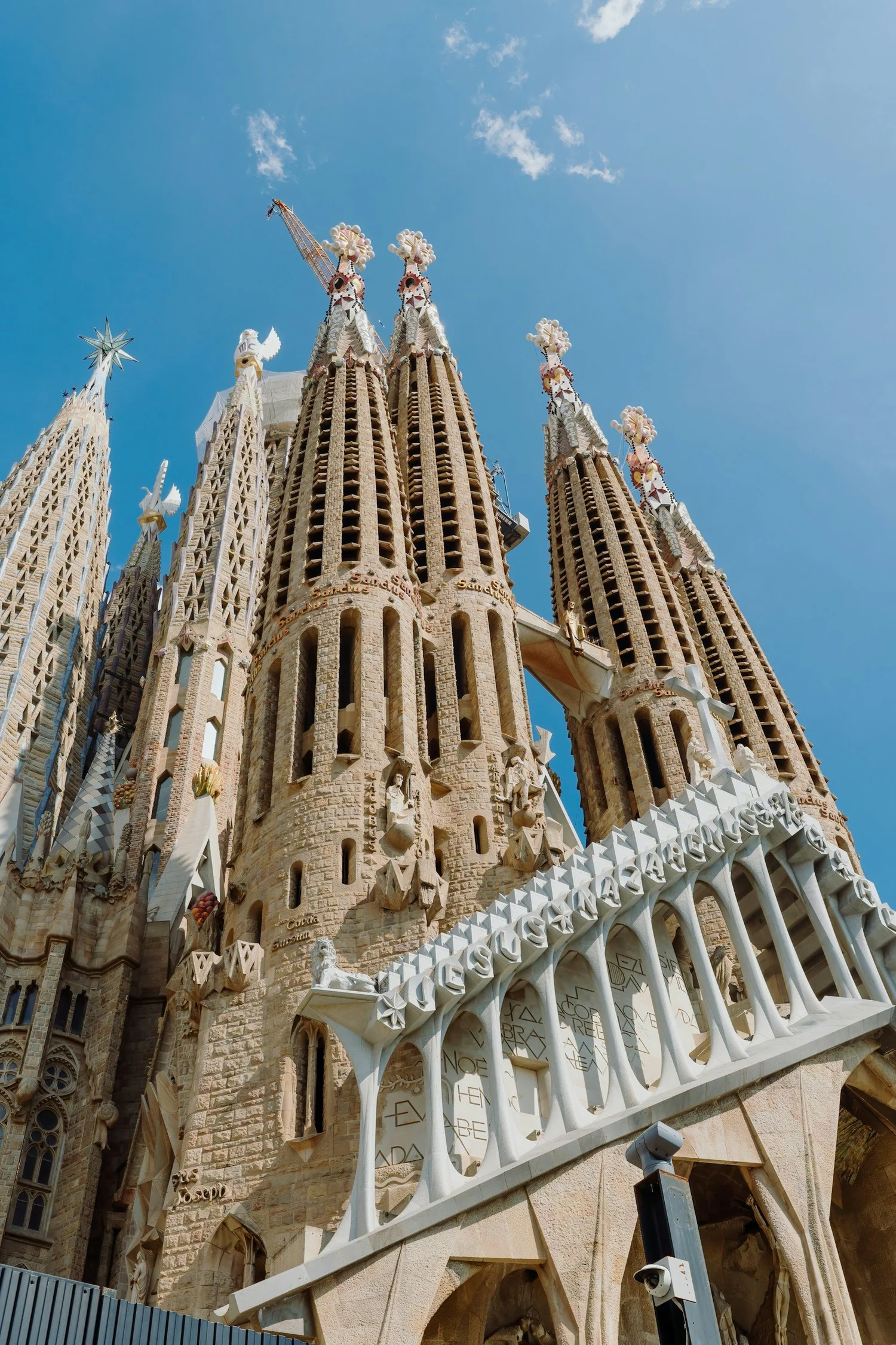 Close-up view of the Sagrada Família church in Barcelona, Spain, showing its ornate spires and detailed stonework against a blue sky.