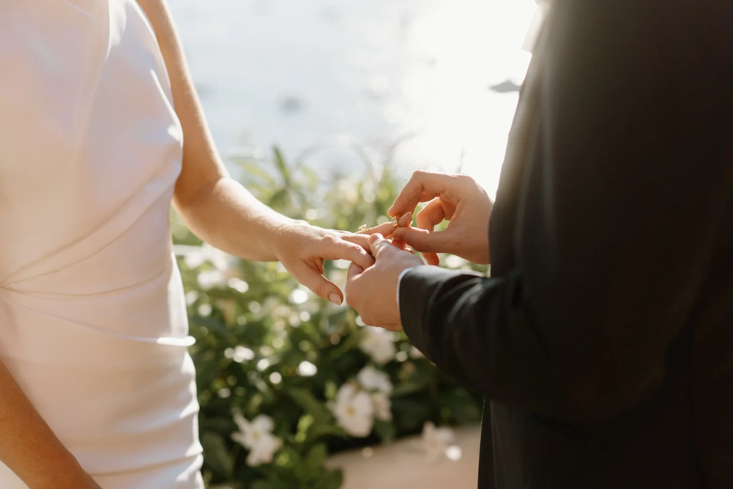 Person in a white dress holding hands with another person in a black suit during a wedding ceremony.